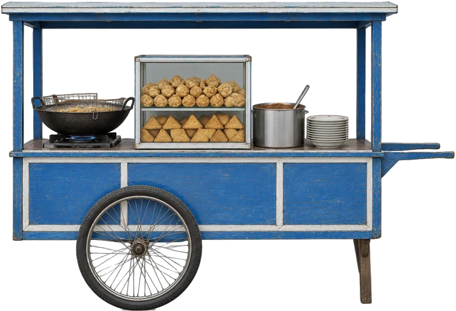 Gerobak batagor biru: wajan besi di atas kompor, etalase kaca penuh batagor dan tahu goreng, panci bumbu kacang, tumpukan piring.
